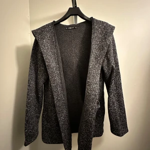 Grå kofta - Helt oanvänd och skön kofta från New Yorker i storlek XL. Jättefin grå färg och en stor luva som är perfekt nu till hösten och vintern under jackan eller bara så som den är!