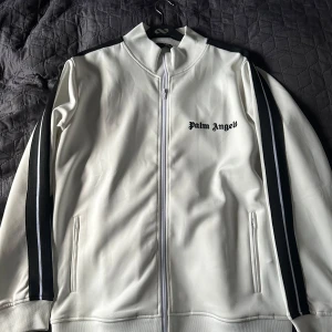 Vit track jacket från Palm Angels - Säljer en snygg vit Palm Angels top i storlek S. Den är i mycket bra skick och knappt använd (9/10). Passar till allt från en stilig outfit💰till en chill kväll. Passar även en mindre M. Hör av er vid funderingar! Matchande byxor finns även att köpa till!