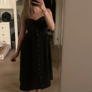 Svart klänning - Säljer min söta svarta klänning från HM i storlek 38. Klänningen är bekväm och har knappar framtill, den är i mycket bra skick och säljer då jag ej har användning av den.