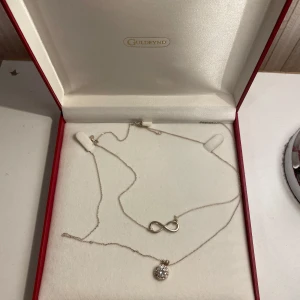 Smyckeset med halsband från Guldfynd - Säljer ett elegant smyckeset från Guldfynd med två halsband. Det ena har ett oändlighetstecken och det andra en gnistrande rund berlock. Perfekt för att ge en touch av stil till vilken outfit som helst. Kommer i originalförpackning. Priset går alltid att diskuteras🤩