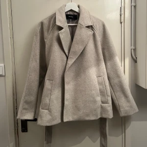 Beige kappa med band  - Säljer en beige kappa från Vero Moda i nyskick! Endast använt 1-2 gånger. Storlek S