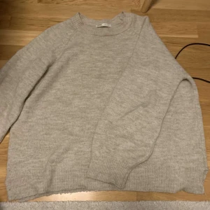 Beige stickad tröja - Mysig beige stickad tröja i bra skick. Perfekt för kyliga dagar med sin varma och bekväma design. Tröjan har långa ärmar och ribbade kanter som ger en klassisk look. Passar perfekt till både vardag och mysiga hemmakvällar.