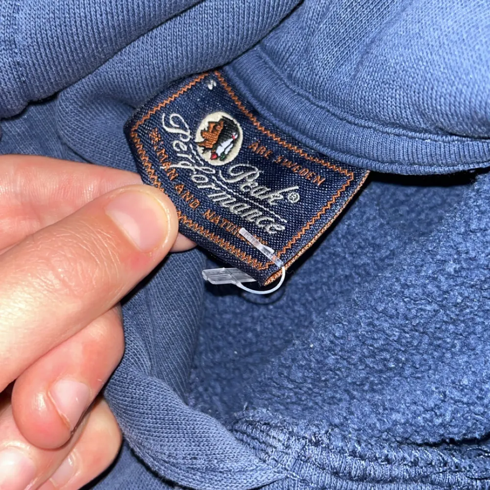 Säljer en blå hoodie från Peak Performance i bra skick. Den har en liten fläck på framsidan men är annars i fint skick. Perfekt för höst och vår med sin mjuka och bekväma passform. Stor logga på ärmen ger en sportig look. Hör av dig vid intresse!. Hupparit & Collegepaidat.