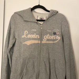 Grå hoodie från Lexington - Säljer en snygg och bekväm grå hoodie från Lexington. Den har en dragkedja framtill och en mysig huva. Knappt använd 