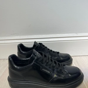 Svarta sneakers från Louis Vuitton - Säljer ett par stilrena svarta sneakers från Louis Vuitton i skinn. De har klassisk snörning och en diskret logga på sidan. Perfekta för både vardag och fest. Skorna är i mycket bra skick och redo för nya äventyr!