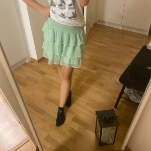 Mintgrön volangkjol - Säljer en superfin mintgrön kjol med volanger. Perfekt för sommardagar eller en festlig kväll. Kjolen har en elastisk midja för bekväm passform och är gjord i ett lätt och luftigt material. Den är kort och passar perfekt med en enkel topp eller blus. 🥰