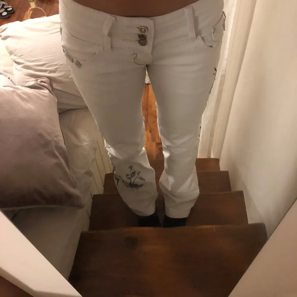 Säljer ett par vita jeans med snyggt Blom brodieri med diamanter på och diamant detaljer runt om fickorna i bak💗. Jeans & Byxor.