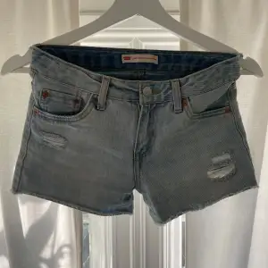 Säljer ett par Levi's Girlfriend Shorty shorts i ljusblå denim. De har en avslappnad passform med slitna detaljer fram och klassiska femficksdesign. Perfekta för sommardagar och festivaler! 🕶️