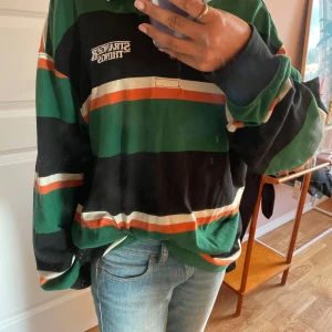 Randig tröja från H&M x Stranger Things - En grön, orange, vit och svart tröja med krage.