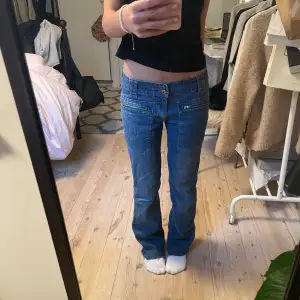 Säljer ett par snygga blå jeans från Caramelle med coolt rosa fjärilsbroderi på bakfickorna. De har en straight/bootcut ish passform och är lågmidjade med dubbla knappar och dragkedjor fram. Dom är nerklippta där nere för att dom ska passa mig som är 160cm lång, men dom är fortfarande lite långa på mig💝.