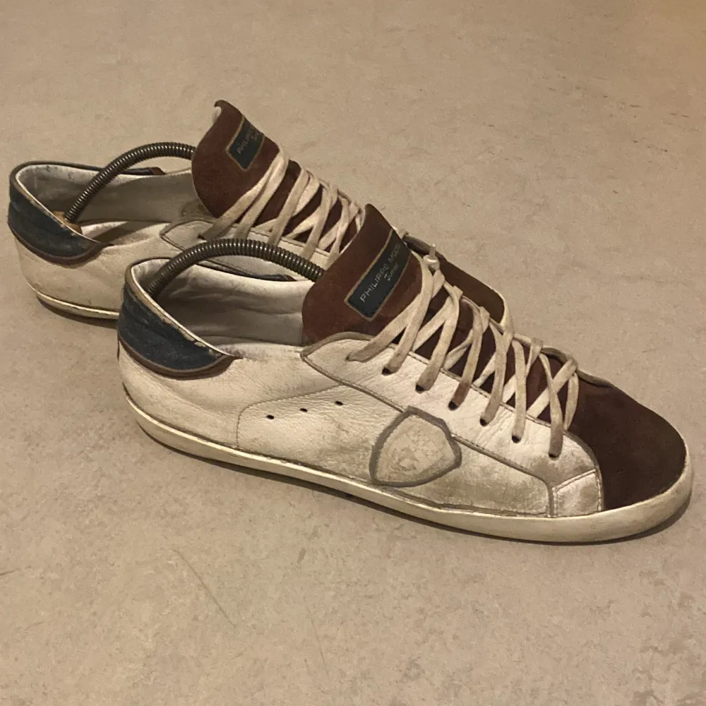 Säljer ett par Philippe Model sneakers i beige och brun mocka med skinn. De har en snygg vintage-look med snörning och en bekväm passform. Perfekta för både vardag och festliga tillfällen. Lite slitna men fortfarande i bra skick.. Skor.