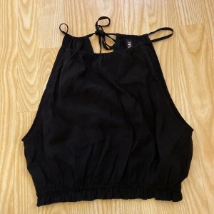 Sött linne💞 - Snygg svart ärmlös topp från Zara i storlek S. Perfekt för sommardagar eller en utekväll. Den har smala axelband och en knytning i nacken för en justerbar passform. Elastisk nederkant för en bekväm och stilren look. Super bra skick använd endast en gång💞💞 