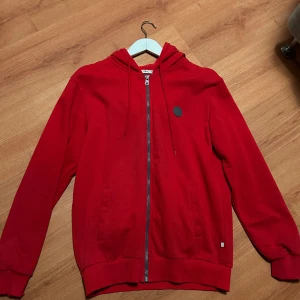 Zip hoodie - Säljer en snygg röd hoodie från LTB i storlek M, köpt från best secret. Den har en dragkedja framtill och en praktisk huva med snören. Perfekt för både höst och vinter, och den är i mycket bra skick. Hör av er vid frågor eller funderingar!