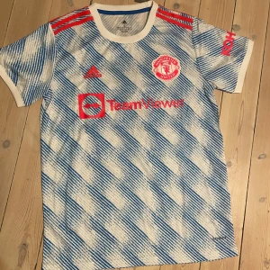Manchester United Jersey från Adidas - Säljer en Manchester United Jersey från Adidas i nyskick. Tröjan har korta ärmar och är i storlek S. Den har 'Ronaldo 7' tryckt på ryggen. Perfekt för fotbollsfans! ⚽