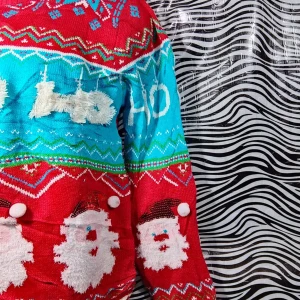 Jultröja med tomtemotiv - Säljer en färgglad jultröja med tomtemotiv och texten 'Ho Ho Ho'. Tröjan är röd och blå med vita detaljer och har ett festligt mönster. Perfekt för julfirandet! 🎅