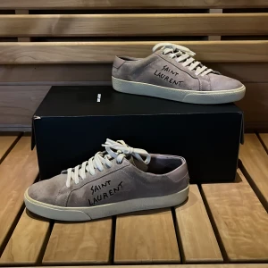 Grå mocka sneakers från Saint Laurent - Säljer ett par snygga grå sneakers i mocka från Saint Laurent. Dom är i riktigt bra skick och är i storlek 39. Vid frågor och funderingar är det bara att höra av sig.