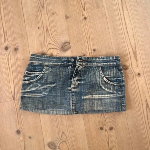 Mini Jeanskjol  - Säljer en cool jeanskjol i sliten stil. Den är kort och har en klassisk femficksdesign med knapp och dragkedja fram. Perfekt för en avslappnad look i sommar eller fest! säljer pga den var för stor för mig:(