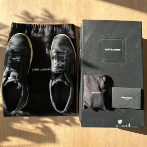 Yves Saint Laurent sneakers  - Populära och eftertraktade YSL sneakers i svart. Köpta på Miinto för 5200kr (kvitto bild 5). Skick 6/10, litet tecken på användning genom en gammal lagning på den högra sulan (se bild). Ingår: 2 dustbags, skokartong, wrapping och extra skosnöre.