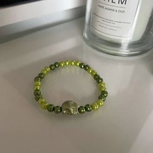 Grönt pärlarmband med dödskalle - Snyggt armband med gröna pärlor och en cool dödskalle i mitten. Perfekt för att ge din outfit en edgy touch. Passar både till vardags och fest!