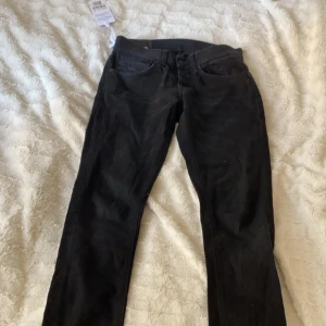 Dondup george jeans - Ett par svarta dondup jeans i modell George med estetiska slitningar fram och bak. Jeansen är måttligt använda och storlek 29-30
