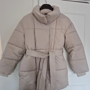 Pufferjacka från Puffit - Mid Length Belted Puffer Jacket. Säljer en puffer jacket från Puffit (Go.G.G) i storlek S. Färg: creme. Helt ny och aldrig använd, tagit bort etiketten dock. Trendar på tiktok.