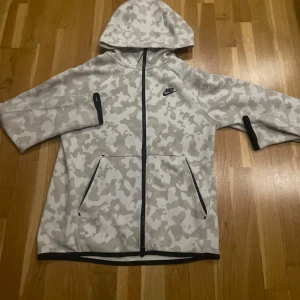 Vit Nike tech Camo kofta  - Säljer min Vita Nike tech Camo kofta, storlek S. Väldigt bra skick, säljer pga att den inte passar mig längre.