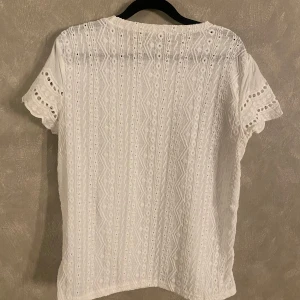 Vit blus från Shein - Säljer en vit blus från Shein med korta ärmar och ett vackert broderat mönster. Blusen är tillverkad i polyester och har en luftig passform, perfekt för varma dagar.🌸🌞