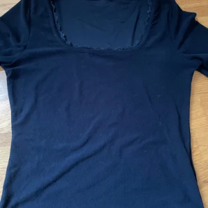 BUDA PRIS: Marinblå långärmad topp med spetsdetaljer - Snygg marinblå långärmad topp med spetsdetaljer vid halsringning och ärmslut. Perfekt för en stilren look.