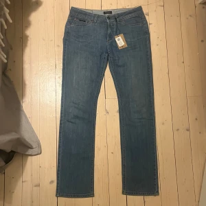 Blå jeans från Gant - Snygga blå jeans från Gant med broderad logga i orange på bakfickan Köpta på Sellpy, men för stora för mig, därför säljer jag! Perfekta för en avslappnad stil. Midjemått rakt över: 40cm Innerbenslängd: 76cm