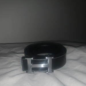 H bälte  - Snyggt svart skärp i skinn med ett stilrent silverfärgat spänne. Perfekt för att ge en elegant touch till din outfit. Passar både till jeans och kostymbyxor.