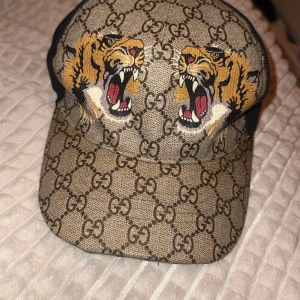 Gucci keps Tiger - Snygg Gucci keps med ikoniskt mönster och coolt tigerbroderi framtill. Justerbar passform för att sitta perfekt. Kvitto finns, skriv privat för mer bilder bara seriösa köpare. Kommer med låda och tillbehör 
