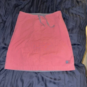 Rosa kjol från Jay Jays - Snygg rosa kjol från Street One med en praktisk dragsko i midjan. Kjolen har en enkel design med en liten logotypdetalj vid fållen. Perfekt för en avslappnad stil.