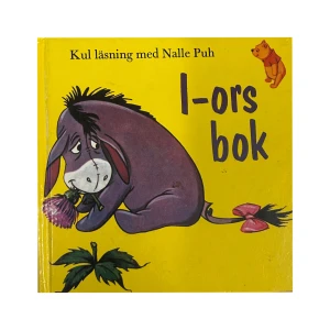 I-ors bok - En färgglad barnbok med I-or från Nalle Puh. Boken har en gul framsida med en illustration av I-or som håller en blomma. Perfekt för unga läsare som älskar äventyr i Sjumilaskogen.