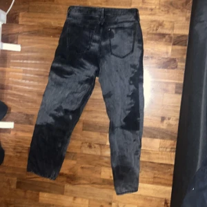 Coola jeans  - Snygga svarta jeansbyxor med en klassisk design. De har en rak passform och är perfekta för en stilren look. Byxorna har fickor fram och bak samt knappar och dragkedja i gylfen. 