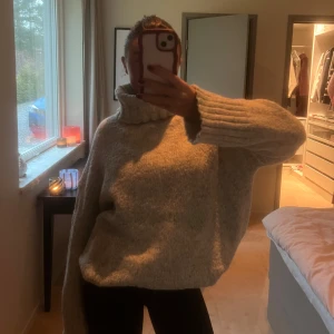 Grå stickad polotröja - Mysig grå stickad polotröja med långa ärmar och en hög krage. Perfekt för kyliga dagar när du vill hålla dig varm och bekväm. Tröjan har en avslappnad passform som ger en skön känsla.