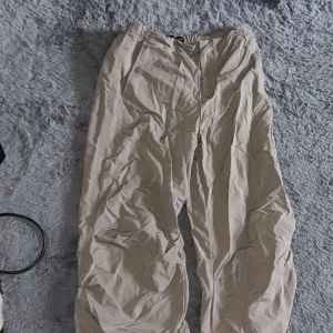 Beige byxor med resårmidja - Säljer ett par bekväma beige byxor med resårmidja. Perfekta för en avslappnad stil. Byxorna har en loose passform och är tillverkade i ett lätt material.