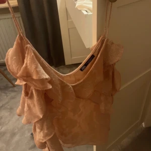 Rosa volanglinne från Zara - Säljer ett sött beige linne från Zara med volangdetaljer. Linnet har tunna axelband.