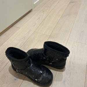 Svarta boots med paljetter - Snygga svarta boots täckta med glittrande paljetter. Perfekta för att ge en extra touch till din outfit. De har en bekväm passform och är idealiska för kyligare dagar.