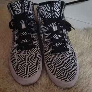 Sneakers från Supra - Snygga svartvita sneakers från Supra med ett iögonfallande geometriskt mönster. Skorna har snörning och två praktiska dragkedjor på båda sidorna för enkel på- och avtagning. Perfekta för en trendig och bekväm stil. Nyköpt pris är 499kr, säljer för 199kr men pris går att diskutera💕🌸