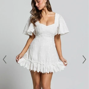 Vit blommig klänning från Showpo - studentklänning - Superfin vit klänning från Showpo med blommigt mönster och volangdetaljer. Helt ny med lappen kvar. Perfekt för sommaren eller som studentklänning🌟🌟