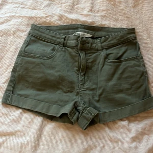 Gröna shorts från H&M - Snygga gröna shorts från H&M med normal passform. De har klassiska femficksdetaljer och är tillverkade i ett bekvämt bomullsmaterial. Perfekta för en avslappnad stil.