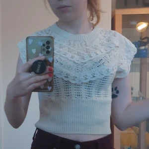 Vit stickad topp/väst med spetsdetaljer - Säljer en söt vit stickad topp/väst med vackra spetsdetaljer på bröstet. Toppen är kortärmad och croppad. Storlek S från Cider, bra skick (: