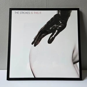 The Strokes - Albumaffisch, 31.5x31.5cm - The Strokes - Is This Is albumaffisch, 31.5x31.5cm. Helt ny - Passar bra i IKEAs tavelram Lomviken!  Skickas i papprulle - Ramen ingår inte!