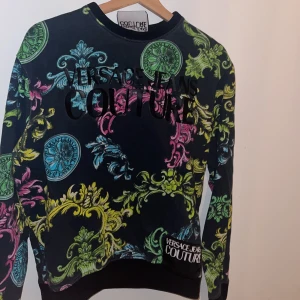 Mönstrad tröja från Versace Jeans Couture - Säljer en färgglad tröja från Versace Jeans Couture med ett iögonfallande mönster i grönt, rosa, blått och gult.Perfekt för dig som vill sticka ut!