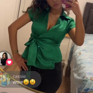 Grön blus med knytning - Snygg grön blus med knytning i midjan och korta ärmar. Perfekt för en stilren look med en djup v-ringning och krage.