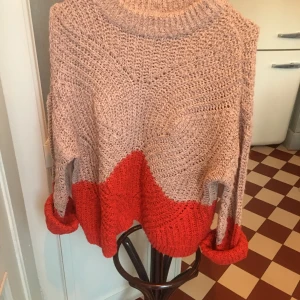 Beige och röd stickad tröja från Object - Säljer en snygg stickad tröja från Object i beige och rött. Tröjan har en avslappnad passform med långa ärmar och en bred ribbad kant vid ärmslut och nederkant. Perfekt för kyliga dagar!