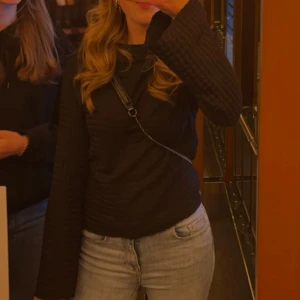 Svart topp i jerseykvalitet med struktur - Säljer en stilren svart ribbad tröja med långa och utsvängda ärmar 🫶🏽.                                                         Köparen står för frakten! 💕