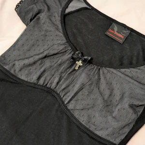 Svart tee med spetsdetaljer och kors - Bekväm och stretchig topp