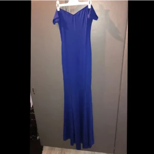 Blå långklänning - Elegant blå långklänning med offshoulder-design. Perfekt för en festlig kväll med sin smickrande passform och stilrena look. Klänningen har en vacker v-ringning och är tillverkad i ett mjukt material som ger en fin siluett. Passar super bra till bal eller liknade event. Endast använt den en gång. 