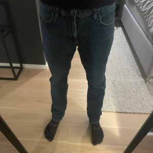 Blå jeans från Lee - Säljer ett par klassiska blå jeans från Lee. De har en straight passform och normal midja. Jeansen har en snygg tvätt och är perfekta för en avslappnad stil. De har både knappar och dragkedja framtill. Priset är inte hugget i sten. Skriv vid funderingar!